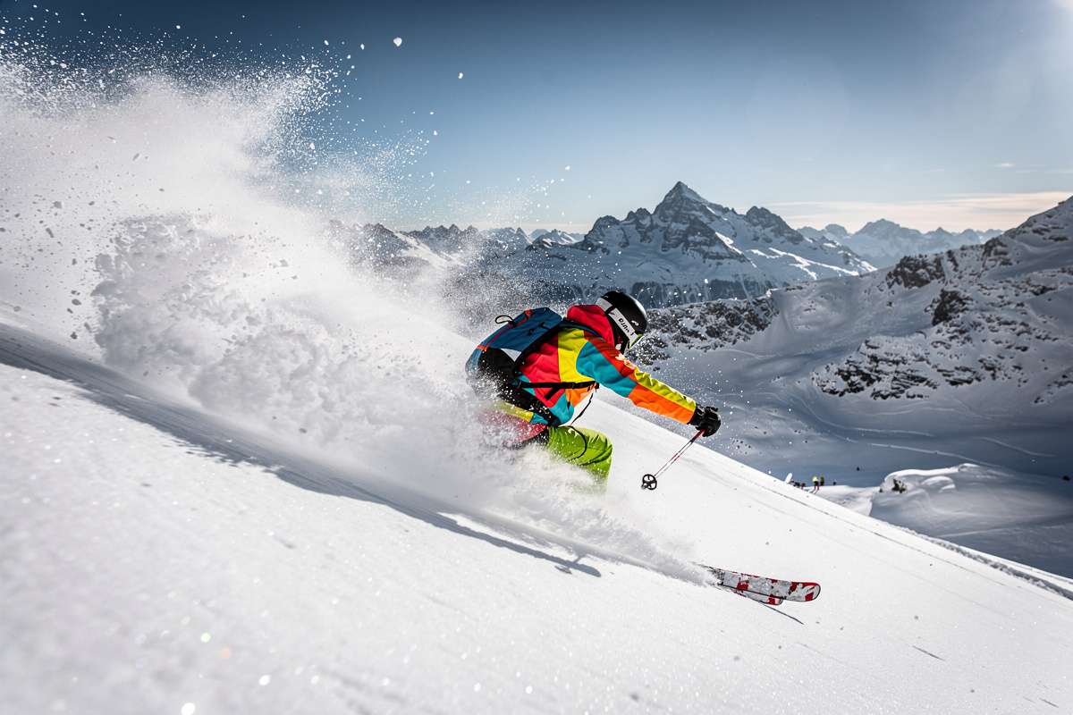 Action shot of a skier kicking up powder on a steep slope